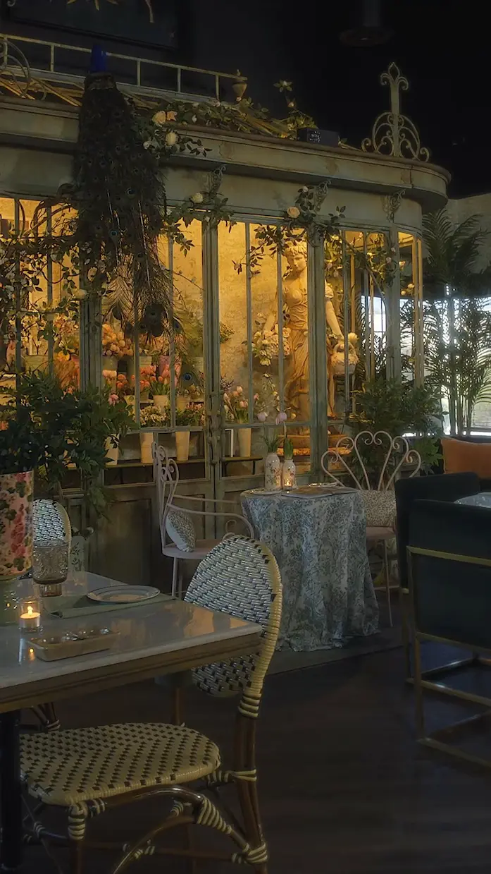 A beautifully decorated event space with lush greenery, a classical statue, and warm ambient candle lighting, set up for an elegant corporate gathering in San Diego.