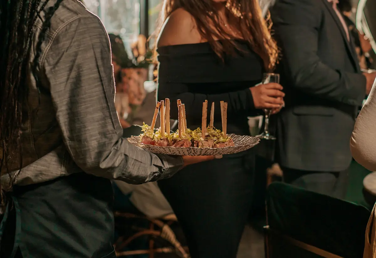 A Gather Catering server presenting a platter of gourmet brunch skewers to guests at a social event in San Diego